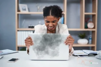 Frustrated user holding a laptop showing signs of overheating like warning icons and fan noise